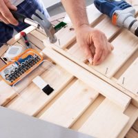 hands-driving-nail-with-hammer-into-wooden-shelf